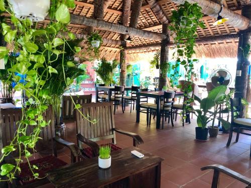 美奈MiNhon Hotel Muine的一间设有桌椅的餐厅,种植了植物