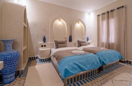 梅尔祖卡Riad Chebbi的一间卧室设有一张大床和一个蓝色的花瓶。