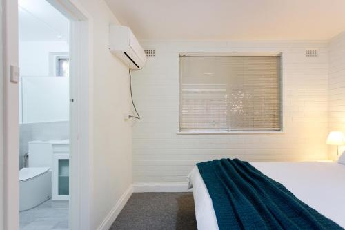 珀斯Hensman 5 - 1BRM Unit with Courtyard & Parking的卧室配有床、浴缸和窗户。