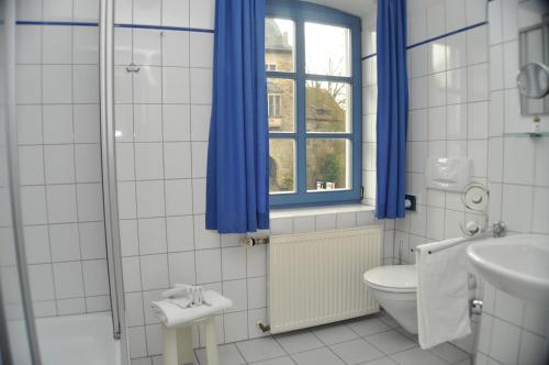 Schaumburg斯商姆博格里特尔酒店的一间带卫生间的浴室和一个带蓝色窗帘的窗户。