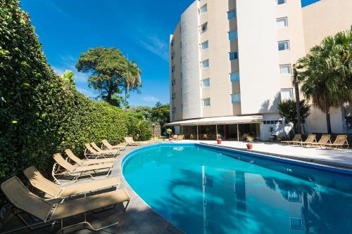 坎皮纳斯坎皮纳斯里加别墅酒店的一座带躺椅的游泳池位于大楼旁