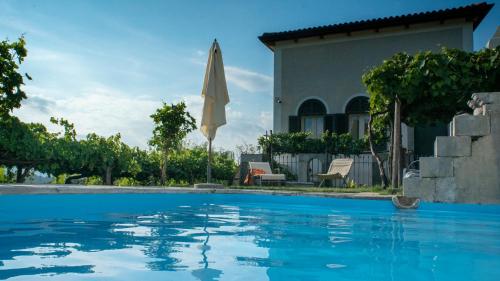 莫尔曼诺Il Casino di Donna Maria的一座带遮阳伞的房屋前的游泳池