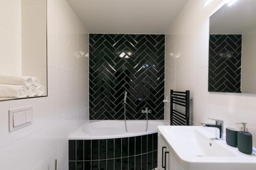 比尔森Avantgarde apartments的白色的浴室设有浴缸和水槽。
