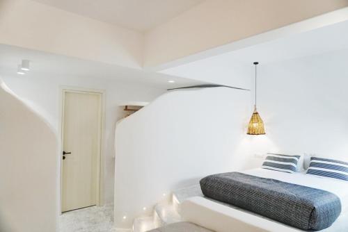 纳克索乔拉加里尼酒店的卧室拥有白色的墙壁,配有一张带蓝色枕头的床。