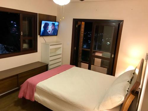瓜拉雷马Casa Bela Vista的卧室配有一张床,墙上配有电视。