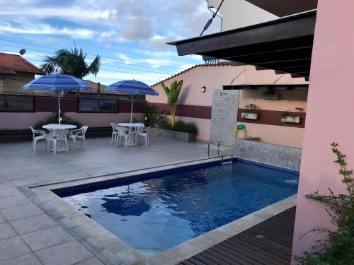 瓜拉雷马Casa Bela Vista的房屋旁的游泳池配有桌子和遮阳伞
