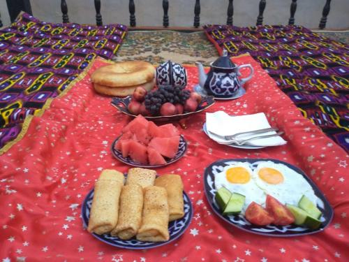 布哈拉Zafar Family Guesthouse的红色桌布上带早餐盘的桌子