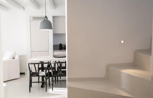 梅加洛克里Philosophia Luxury Villa的厨房以及带白色墙壁和黑色椅子的用餐室。