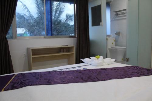 西哈努克Don Bosco Guesthouse的一间卧室配有一张带紫色床单的床和窗户。