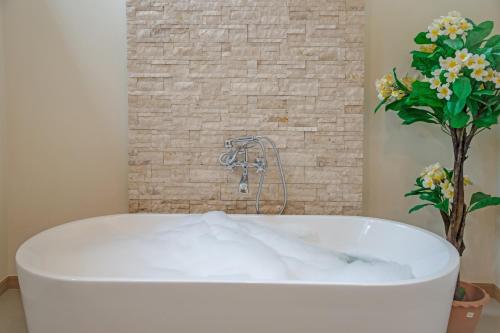 拉威海滩Villa Karina的植物浴室内的白色浴缸