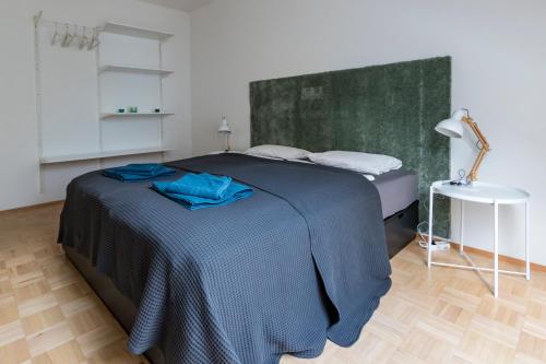 格拉茨Flataid Apartment Obere Bahnstraße - Grazer Messe的一间卧室配有一张带蓝色床单的床和一张桌子。
