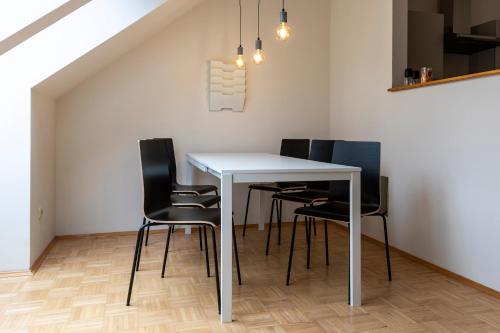 格拉茨Flataid Apartment Obere Bahnstraße - Grazer Messe的一间配备有白色桌子和黑色椅子的用餐室