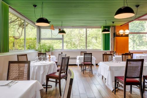 波雷塔泰尔梅桑多利酒店的餐厅设有白色的桌椅和窗户。