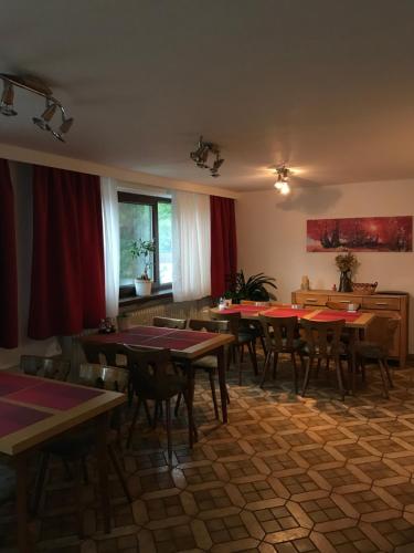 博登迈斯Hotel Tannenhof的一间配备有桌椅和红色窗帘的用餐室