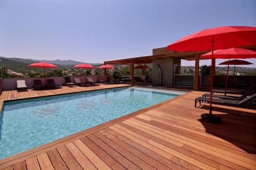 波尔蒂乔Residence ACQUA LINDA Porticcio的甲板上配有红色遮阳伞的游泳池