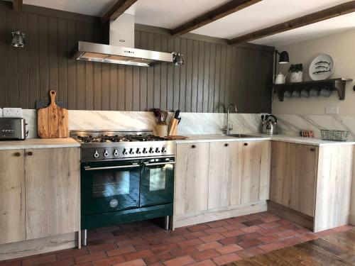 巴克斯顿Cuckoostone Barn的厨房配有木制橱柜和炉灶。
