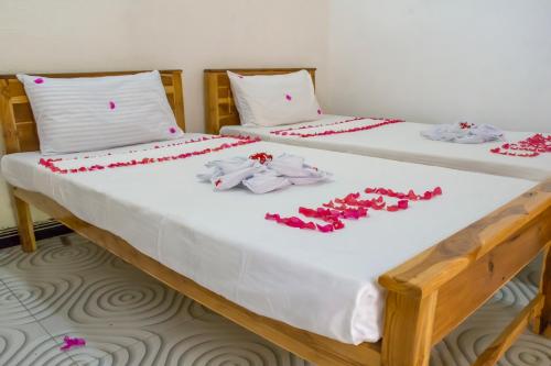 阿鲁甘湾Beach Lagoon Parans的两张带白色床单和红色鲜花的床