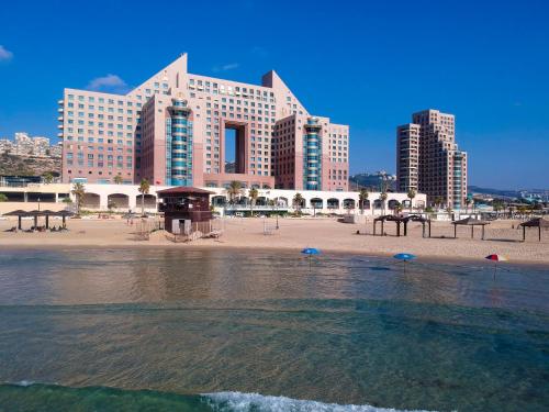 海法Almog Haifa Israel Apartments מגדלי חוף הכרמל的海滩上设有一座大型建筑,还有一些水