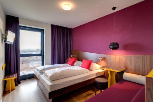 美因河畔法兰克福法兰克福机场梅宁阁酒店的酒店客房带一张床和紫色的墙壁