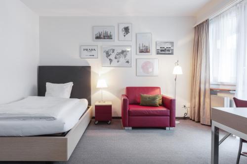 苏黎世EMA House Serviced Apartments Seefeld的酒店客房,配有一张床和一张红色椅子