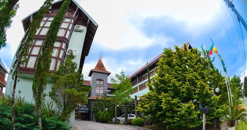 格拉玛多Hotel Aconchego da Serra的一座有旗帜的建筑和一座树木繁茂的建筑