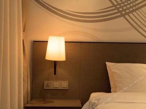 兰州如家精选酒店兰州张掖路步行街店的一间卧室配有一张床,上面有灯