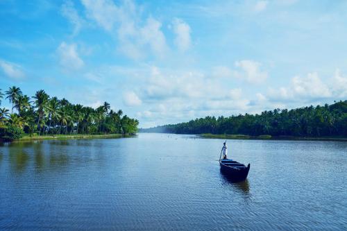 可瓦兰Taj Green Cove Resort and Spa Kovalam的棕榈树河畔的男人