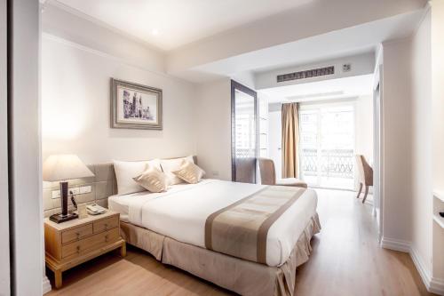 曼谷希望之地素坤逸 24 號酒店的白色的卧室设有床和窗户