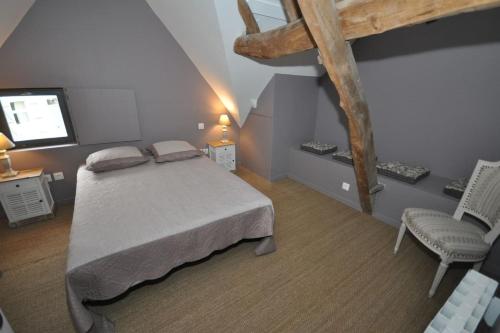 BerséeGîte de la Broderie的一间卧室配有一张床、一把椅子和电视