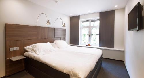 Varsseveld德普罗格霍恩餐厅酒店的一间卧室设有一张大床和一个窗户。
