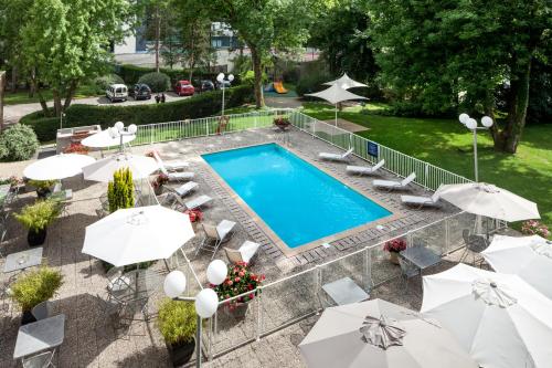 贝桑松贝桑松诺富特酒店的享有带椅子和遮阳伞的游泳池的上方景致