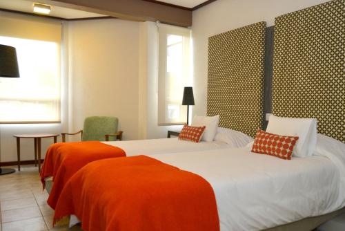 埃尔卡拉法特埃尔卡拉法特ACA酒店的配有橙色床单的酒店客房内的两张床