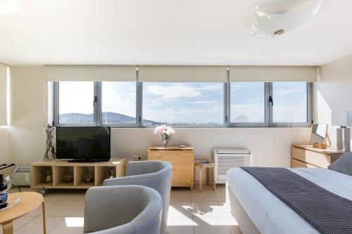 雅典GB Athens View Luxury Suite的一间卧室配有一张床和一台电视,部分设有窗户。