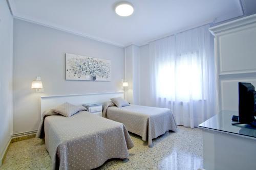 Vioño艾尔卡普里科旅馆的酒店客房设有两张床和电视。