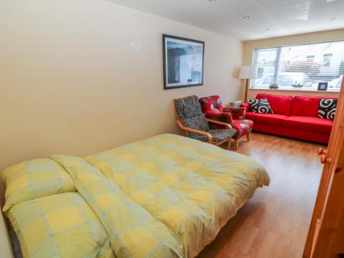普尔赫利Lliwedd的一间卧室配有一张床和一张红色的沙发