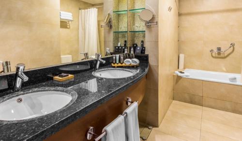 康塞普西翁MDS Hotel Concepción的浴室配有两个盥洗盆和浴缸。