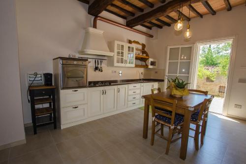 蒙泰斯佩尔托利Poggio al Sole的厨房配有白色橱柜和木桌