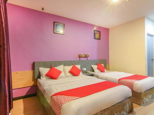 山打根Super OYO 43930 Hotel Esplanade的紫色墙壁客房的两张床