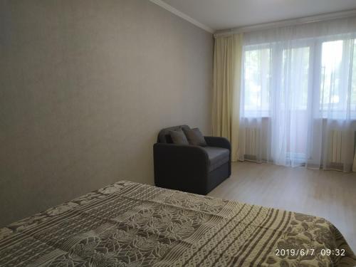 敖德萨Апартаменты на Ивана и Юрия Лип的卧室配有床、椅子和窗户。