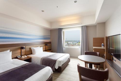 东京Haneda Excel Hotel Tokyu Haneda Airport Terminal 2的酒店客房设有两张床、一张桌子和电视。