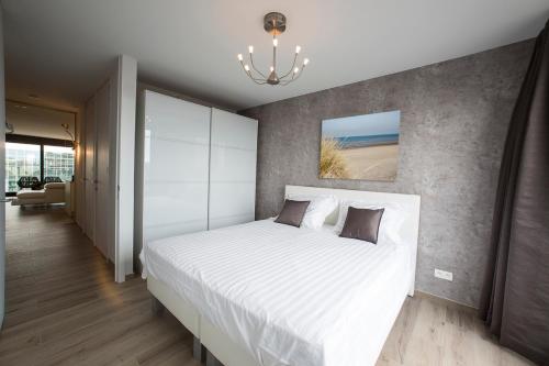 科克赛德Design appartement Zeelaan Koksijde的卧室配有一张白色大床和吊灯。