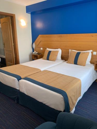 里斯本智利多之栈酒店的蓝色墙壁的酒店客房内的两张床