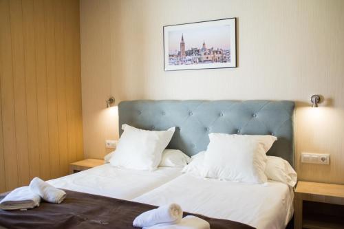 塞维利亚广场酒店的一间卧室配有一张带白色床单和蓝色床头板的床。