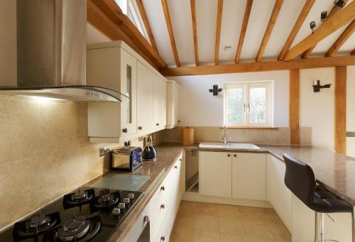 ThorndonOwl's Hoot的厨房配有白色橱柜和炉灶烤箱。
