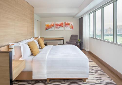 马尼拉Brittany Hotel BGC的卧室设有一张白色大床和大窗户