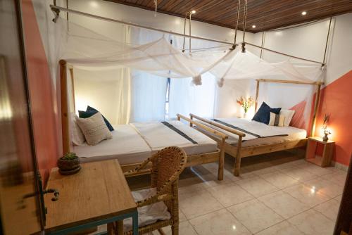 基加利OMX Hotel Kimi的一间卧室配有两张床和一张桌子。