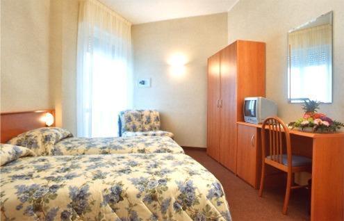科莫尹哥帝娜酒店的酒店客房设有一张床和一张带电视的书桌。