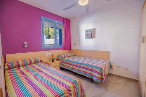 坎布里尔斯伦托马尔科斯塔福德公寓的配有粉红色和紫色墙壁的客房内的两张床