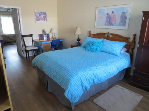 Burns LakeBurns Lake Bed and Breakfast的一间卧室配有蓝色的床和一张书桌