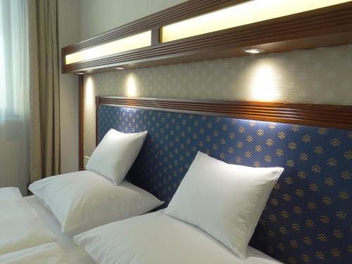 德布勒森森特鲁姆酒店的一间卧室配有两张带白色枕头的床